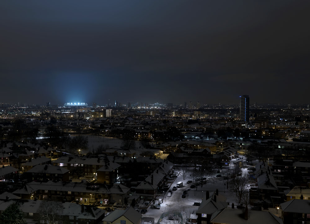 Londons Olympic Stadium lights up for the first time as snow falls across the city